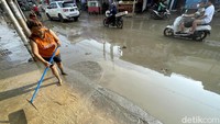 Seorang warga membersihkan area rumahnya dari sisa-sisa banjir di kawasan Perumahan Villa Nusa Indah, Kota Bekasi.