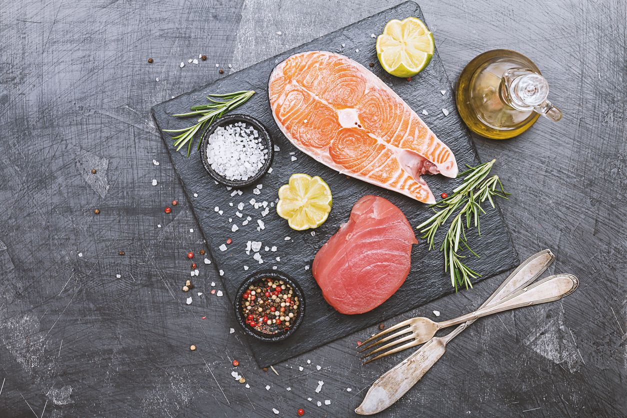 Raw tuna and salmon steak and ingredients for cooking on a dark background. Top view