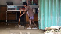 Seorang warga tampak membersihkan lumpur usai banjir merendam rumahnya di kawasan Bekasi, Kamis (17/2/2022).