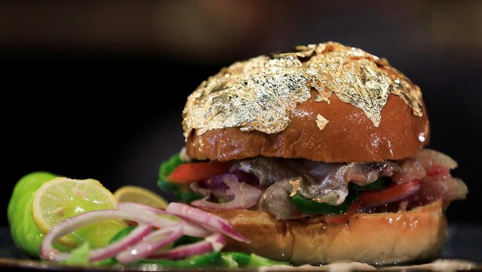 Mencicipi Burger Ikan Asin Bertabur Emas Ala Mesir Hisham Ali, a customer, eats a