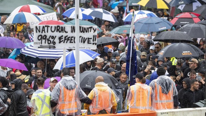 Protesters gather in wet conditions as they voice their opposition to coronavirus vaccine mandates at Parliament in Wellington, New Zealand, Saturday, Feb. 12, 2022. The protest began when a convoy of trucks and cars drove to Parliament from around the nation, inspired by protests in Canada. (Mark Mitchell/NZME via AP)