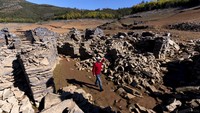 Seorang pria berjalan di antara reruntuhan desa tua Vilar di dekat Pampilhosa da Serra di Portugal bagian tengah, Kamis (17/2/2022). 
