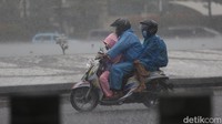 Banyak pengemudi motor menggunakan jas hujan berusaha menerobos hujan yang lebat.  