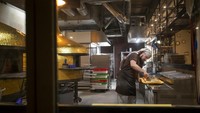 Pembuat pizza menyelesaikan pekerjaanya di Vilnius, Lithuania, Jumat (11/2/2022). Membuat pizza dengan citarasa yang membuat konsumen tersenyum merupakan sesuatu yang tidak bisa dinilai dengan uang.  (AP Photo/Mindaugas Kulbis)