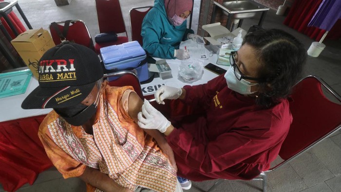 Petugas kesehatan menyuntikkan vaksin kepada lansia saat hari pertama vaksinasi booster COVID-19 di Taman Sekartaji, Kota Kediri, Jawa Timur, Sabtu (19/2/2022). Layanan vaksinasi booster COVID-19 yang akan berlangsung selama 4 hari tersebut pada hari pertama masih tergolong sepi peminat yaitu hanya 54 orang peserta dari target 100 orang per hari. ANTARA FOTO/Prasetia Fauzani/nym.