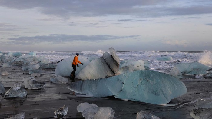 A tourist looks at the blocks of ice that have broken off Jokulsarlon glacier lagoon at Diamond beach during the winter in the southern coast of Iceland February 17, 2022. REUTERS/Nacho Doce TPX IMAGES OF THE DAY