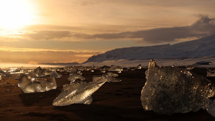A tourist looks at the blocks of ice that have broken off Jokulsarlon glacier lagoon at Diamond beach during the winter in the southern coast of Iceland February 17, 2022. REUTERS/Nacho Doce     TPX IMAGES OF THE DAY