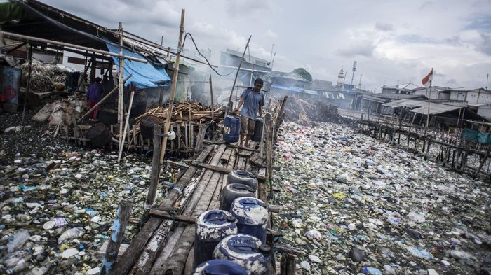 Warga memikul jeriken air melintasi jembatan kayu di antara sampah di kawasan perkampungan nelayan Cilincing, Jakarta, Minggu (20/2/2022). Jelang peringatan Hari Peduli Sampah Nasional (HPSN) 2022, Pemprov DKI Jakarta mengajak warga Jakarta untuk peduli sampah mulai dari lingkungan terdekat minimal dengan cara memilah sampah dari rumah. ANTARA FOTO/Aprillio Akbar/tom.