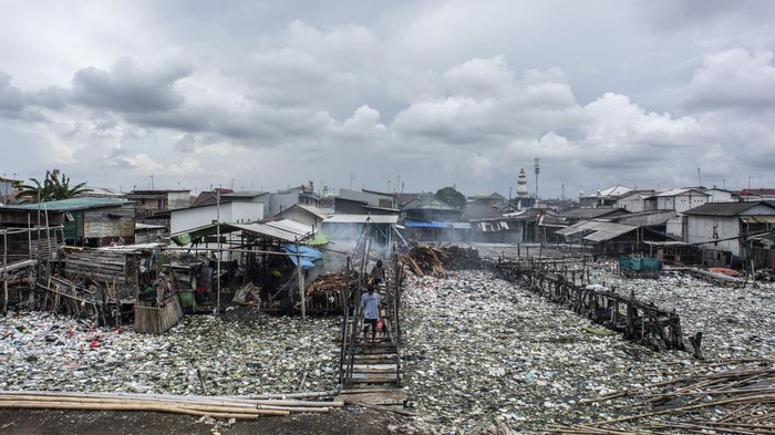 Warga memikul jeriken air melintasi jembatan kayu di antara sampah di kawasan perkampungan nelayan Cilincing, Jakarta, Minggu (20/2/2022). Jelang peringatan Hari Peduli Sampah Nasional (HPSN) 2022, Pemprov DKI Jakarta mengajak warga Jakarta untuk peduli sampah mulai dari lingkungan terdekat minimal dengan cara memilah sampah dari rumah. ANTARA FOTO/Aprillio Akbar/tom.