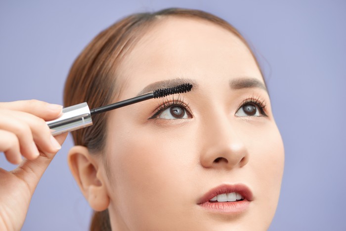1195842197 beautiful young woman applied mascara, studio beauty portrait