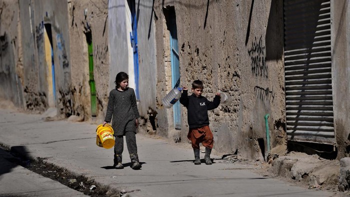 A woman sits on the ground as she cooks in her one room house, in Kabul, Afghanistan, Sunday, Feb. 20, 2022. (AP Photo/Hussein Malla)