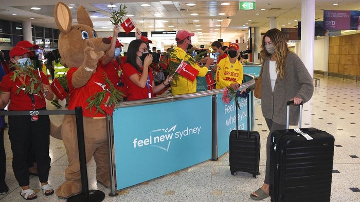 Passengers are welcomed as they arrive at Sydney International Airport in Sydney, Monday, Feb. 21, 2022. International tourists and business travelers began arriving in Australia with few restrictions for the first time in almost two years after the government lifted some of the most draconian pandemic measures of any democracy in the world. (Dean Lewins/AAP Image via AP)