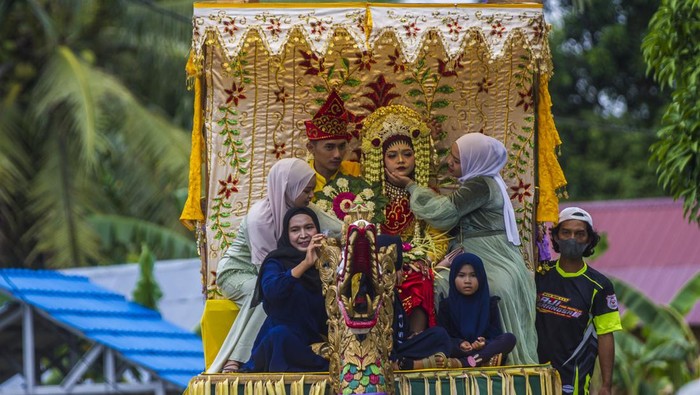 Melihat Tradisi Adat Pengantin Banjar di Kalimantan Selatan Pasangan pengantin mengikuti prosesi Bausung (digendong) saat Tradisi Pengantin Banjar Di Kecamatan Haruyan, Kabupaten Hulu Sungai Tengah, Kalimantan Selatan, Minggu (20/2/2022). Tradisi pengantin tersebut menampilkan berbagai macam seni dan budaya seperti Bearak Naga, Bausung Pengantin, berbalas pantun, dan Bapantul yang merupakan adat istiadat suata perkawinan di Kalimantan Selatan serta melestarikan tradisi turun temurun adat Banjar. ANTARA FOTO/Bayu Pratama S/hp.
