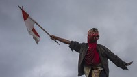 Seorang warga mengibarkan bendara Merah Putih saat berhasil memanjat pinang dengan kesenian Bapantul (Menggunakan Topeng) saat Tradisi Pengantin Banjar Di Kecamatan Haruyan, Kabupaten Hulu Sungai Tengah, Kalimantan Selatan.