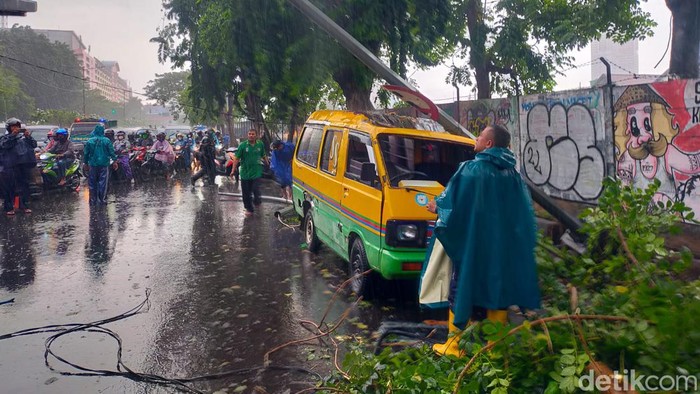 Pohon tumbang terjadi di kawasan Mayangkara, Wonokromo, Surabaya. Pohon dan lampu jalan tumbang menimpa angkot dan mobil