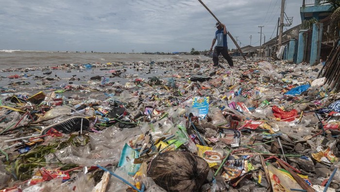 Warga melintasi tumpukan sampah yang terbawa ombak di Teluk Labuan, Pandeglang, Banten, Senin (7/2/2022). Sampah limbah rumah tangga tersebut terbawa oleh gelombang tinggi yang terjadi sejak beberapa hari terakhir di daerah itu. ANTARA FOTO/Muhammad Bagus Khoirunas/rwa.
