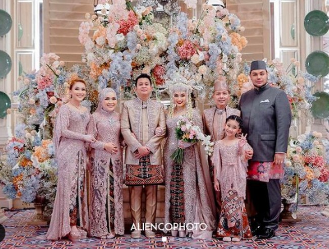 Ia tampil mengenakan hiasan kepala kembang goyang yang menjadi ciri khas pengantin Betawi. Syifa mengenakan kebaya pengantin modern warna pink pastel dengan potongan off-shoulder. Tampak Ayu Ting Ting dan keluarga pun mengenakan busana warna senada. Foto: dok. Youtube, Instagram