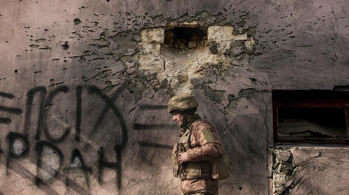 A Ukrainian serviceman walks by a building which was hit by a large caliber mortar shell in the frontline village of Krymske, Luhansk region, in eastern Ukraine, Saturday, Feb. 19, 2022. Ukrainian President Volodymyr Zelenskyy, facing a sharp spike in violence in and around territory held by Russia-backed rebels and increasingly dire warnings that Russia plans to invade, on Saturday called for Russian President Vladimir Putin to meet him and seek resolution to the crisis. (AP Photo/Vadim Ghirda)
