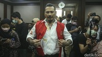 Jerinx hadir mengenakan kemeja putih dengan luaran rompi oranye.