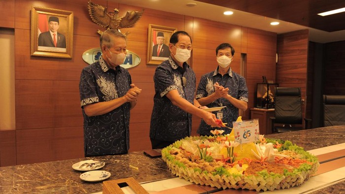 Presiden Direktur BCA Jahja Setiaatmadja (tengah) didampingi Wakil Presiden Direktur BCA Suwignyo Budiman (kiri) dan Wakil Presiden Direktur BCA Armand Wahyudi Hartono (kanan) secara simbolis memotong tumpeng di tengah acara perayaan HUT BCA ke-65 di Jakarta, Senin (21/02/2022).