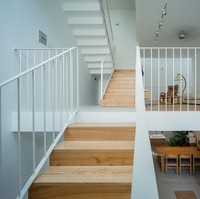 Interior minimalis menyatu dengan karakter rumah yang hadir dengan warna putih. Tangga dan perabotan rumah dari kayu menghadirkan kesan hangat di dalam rumah dan menyatu dengan pohon serta berbagai tanaman yang ada di dalam rumah. Foto: Dok. Quang Tran via Arch Daily