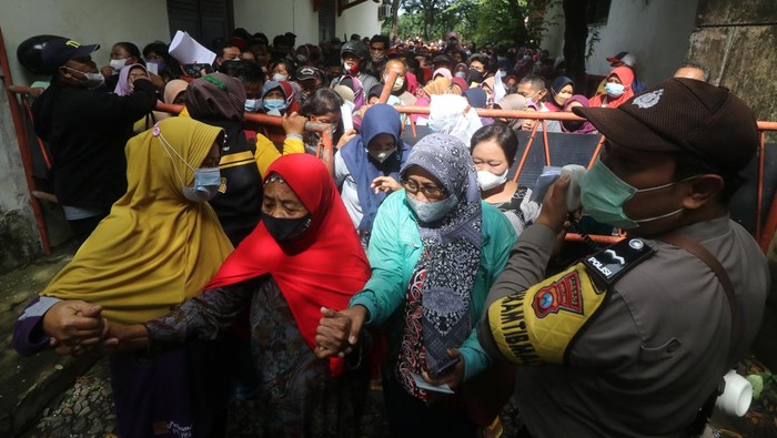 Warga Kediri Desak-desakan Ambil Bansos Sembako Warga menunggu panggilan saat penyaluran dana bantuan Program Sembako tahun 2022 di Kantor Pos Besar, Kota Kediri, Jawa Timur, Selasa (22/2/2022). Penyaluran dana bantuan program sembako senilai Rp600 ribu untuk 3 bulan kepada 11 ribu keluarga penerima manfaat di Kota Kediri tersebut diwarnai kerumunan dan saling dorong karena banyak warga datang tidak sesui dengan waktu yang telah ditentukan pada surat undangan. ANTARA FOTO/Prasetia Fauzani/foc.