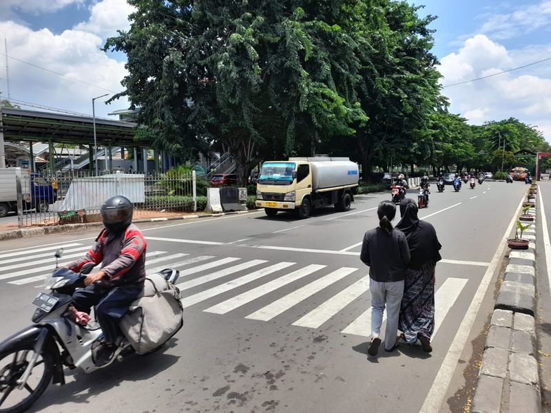 Warga menyeberang menuju akses masuk Stasiun Klender Baru, Jl I Gusti Ngurah Rai, Jakarta Timur. Mereka meminta pembuatan pelican crossing.