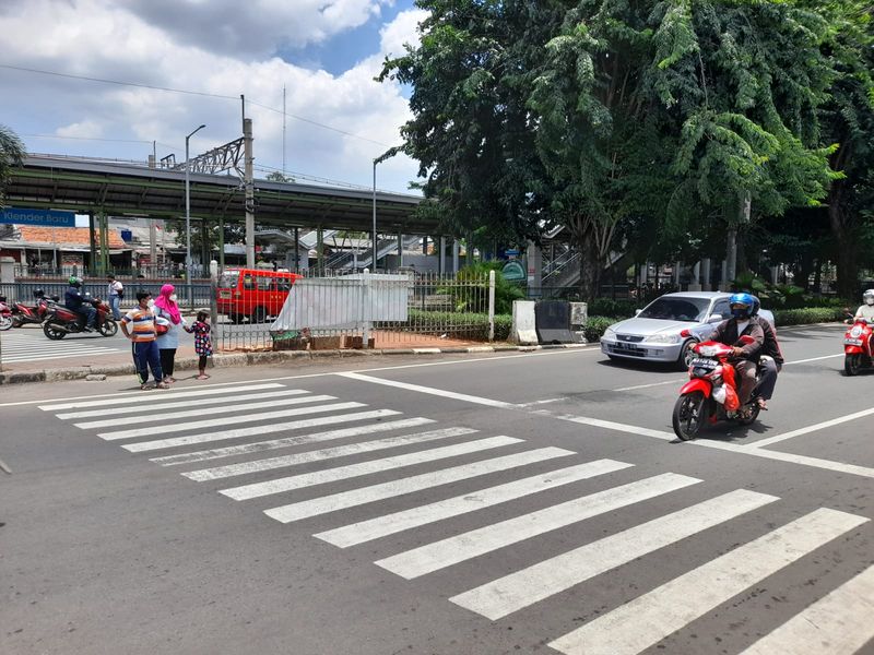 Warga menyeberang menuju akses masuk Stasiun Klender Baru, Jl I Gusti Ngurah Rai, Jakarta Timur. Mereka meminta pembuatan pelican crossing.