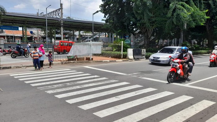 Warga menyeberang menuju akses masuk Stasiun Klender Baru, Jl I Gusti Ngurah Rai, Jakarta Timur. Mereka meminta pembuatan pelican crossing.