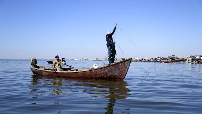 Fishermen stand on the bank of Razzaza Lake, also known as Lake Milh, Arabic for salt, in the Karbala governorate of Iraq, Feb. 14, 2022. The lake was once a tourist attraction known for its beautiful scenery and an abundance of fish that locals depended on. Dead fish now litter its shores and the once-fertile lands around it have turned into a barren desert. (AP Photo/Hadi Mizban)