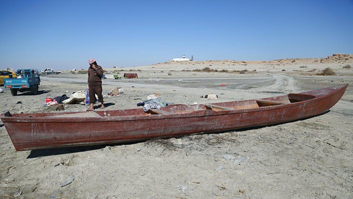 Fishermen stand on the bank of Razzaza Lake, also known as Lake Milh, Arabic for salt, in the Karbala governorate of Iraq, Feb. 14, 2022. The lake was once a tourist attraction known for its beautiful scenery and an abundance of fish that locals depended on. Dead fish now litter its shores and the once-fertile lands around it have turned into a barren desert. (AP Photo/Hadi Mizban)