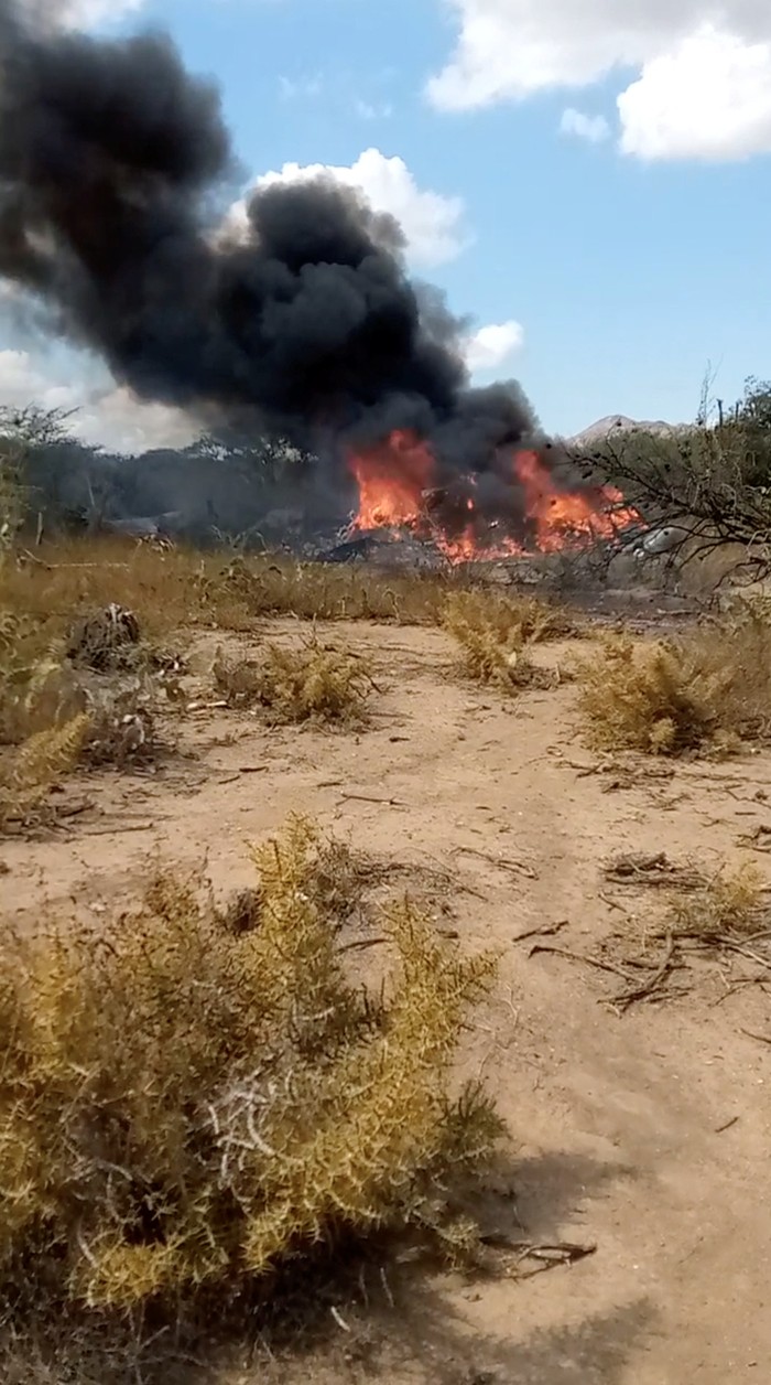 People look at burning debris after a helicopter crash, in Lara, Venezuela, February 22, 2022 in this still image obtained from a video posted on social media. Cristian Caruci Amaro/via REUTERS THIS IMAGE HAS BEEN SUPPLIED BY A THIRD PARTY. MANDATORY CREDIT. NO RESALES. NO ARCHIVES.