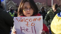 Seorang demonstran membawa poster bertuliskan Welcome to Hell atau selamat datang di Neraka saat menggelar aksi di depan Kedutaan Besar Rusia di Kyiv, Ukraina, di tengah kian tegangnya konflik di antara Ukraina dan Rusia. AP Photo/Efrem Lukatsky.