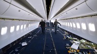  Dua orang pekerja mengangkut kursi penumpang yang dilepas dari dalam pesawat yang akan dialihfungsikan menjadi jet kargo.