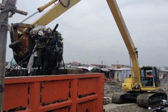 Ekskavator mengangkat tumpukan sampah ke truk pengangkut sampah di kawasan perkampungan nelayan di Kalibaru, Cilincing, Jakut, Rabu (23/2/2022) (ANTARA/HO-Kominfotik Jakut)