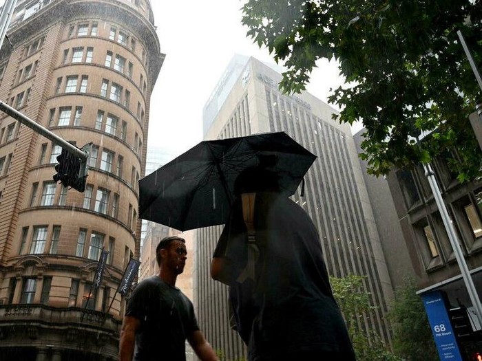 Pedestrians walk in heavy rain in the central business district of Sydney on February 22, 2022. (Saeed KHAN/AFP)