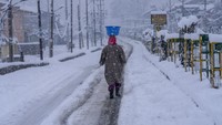 Seorang wanita berjalan di lapangan yang tertutup salju di Srinagar, Kashmir, Rabu (23/2/2022).