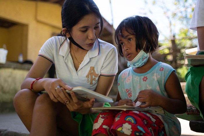 Children select books from the makeshift trolley which serves as a mobile library, near the railroad, in Tagkawayan, Quezon Province, Philippines, February 15, 2022. Picture taken February 15, 2022. REUTERS/Lisa Marie David
