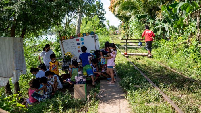 Children select books from the makeshift trolley which serves as a mobile library, near the railroad, in Tagkawayan, Quezon Province, Philippines, February 15, 2022. Picture taken February 15, 2022. REUTERS/Lisa Marie David