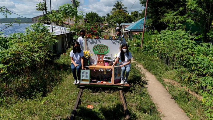 Troli Edukasi Membantu Anak-anak Miskin di Filipina Tetap Belajar Children select books from the makeshift trolley which serves as a mobile library, near the railroad, in Tagkawayan, Quezon Province, Philippines, February 15, 2022. Picture taken February 15, 2022. REUTERS/Lisa Marie David