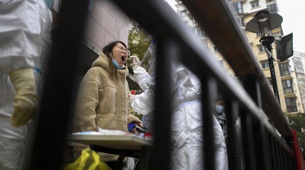 A man holding his bicycle with a school bag on it gets a throat swab during a mass COVID-19 test at a residential compound in Wuhan in central China's Hubei province, Tuesday, Feb. 22, 2022. Wuhan, the first major outbreak of the coronavirus pandemic has reported more than dozen new coronavirus cases this week, prompting the authority to step up precautious measures. (Chinatopix via AP)