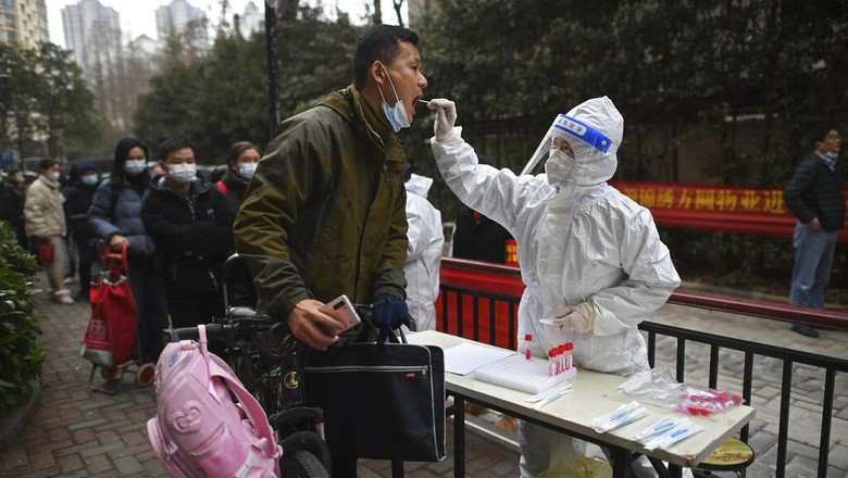 Virus Outbreak China A man holding his bicycle with a school bag on it gets a throat swab during a mass COVID-19 test at a residential compound in Wuhan in central Chinas Hubei province, Tuesday, Feb. 22, 2022. Wuhan, the first major outbreak of the coronavirus pandemic has reported more than dozen new coronavirus cases this week, prompting the authority to step up precautious measures. (Chinatopix via AP)
