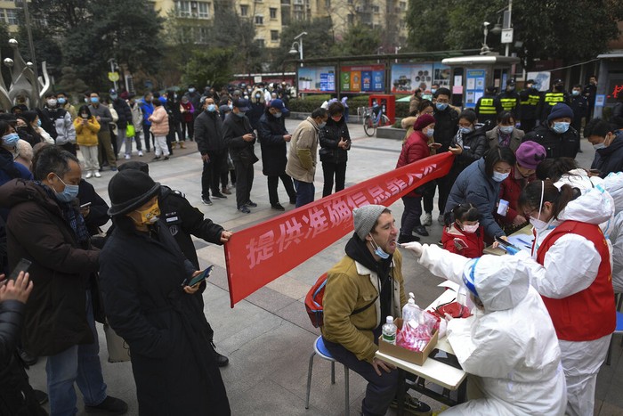 A man holding his bicycle with a school bag on it gets a throat swab during a mass COVID-19 test at a residential compound in Wuhan in central Chinas Hubei province, Tuesday, Feb. 22, 2022. Wuhan, the first major outbreak of the coronavirus pandemic has reported more than dozen new coronavirus cases this week, prompting the authority to step up precautious measures. (Chinatopix via AP)
