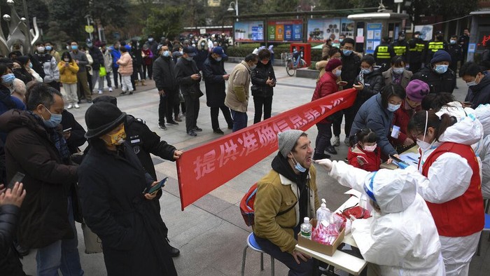 A man holding his bicycle with a school bag on it gets a throat swab during a mass COVID-19 test at a residential compound in Wuhan in central Chinas Hubei province, Tuesday, Feb. 22, 2022. Wuhan, the first major outbreak of the coronavirus pandemic has reported more than dozen new coronavirus cases this week, prompting the authority to step up precautious measures. (Chinatopix via AP)