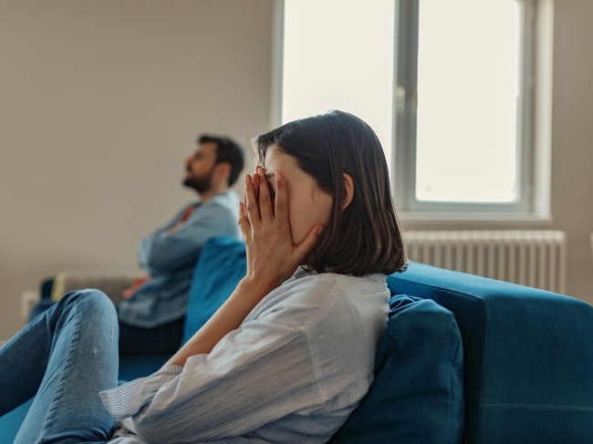 Unhappy Couple After an Argument in the Living Room at Home. Sad Pensive Young Girl Thinking of Relationships Problems Sitting on Sofa With Offended Boyfriend, Conflicts in Marriage, Upset Couple After Fight Dispute, Making Decision of Breaking Up Get Divorced