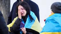 Seorang wanita Ukraina yang sedang berlibur di Norwegia setelah berbicara dengan sang bibi di Ukraina hingga menangis dalam aksi unjuk rasa di depan Kedutaan Besar Ukraina di Oslo. Heiko Junge/NTB/via REUTERS.