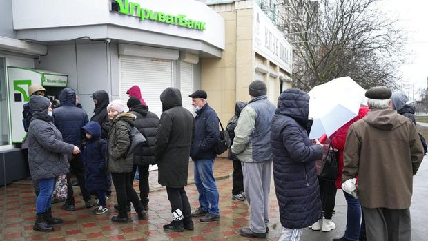 People line up to withdraw their money from an ATM in Mariupol, Ukraine, Thursday, Feb. 24, 2022. Ukraine's border guard agency says that the Russian military has attacked the country from neighboring Belarus. The agency said that the Russian troops unleashed artillery barrage as part of an attack backed by Belarus. (AP Photo/Sergei Grits)