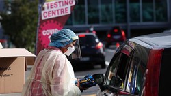 Pekerja kesehatan membagian alat tes antigen cepat kepada warga Selandia Baru. Alat ini dibagikan karena permintaan pengujian COVID-19 meningkat akibat Omicron.