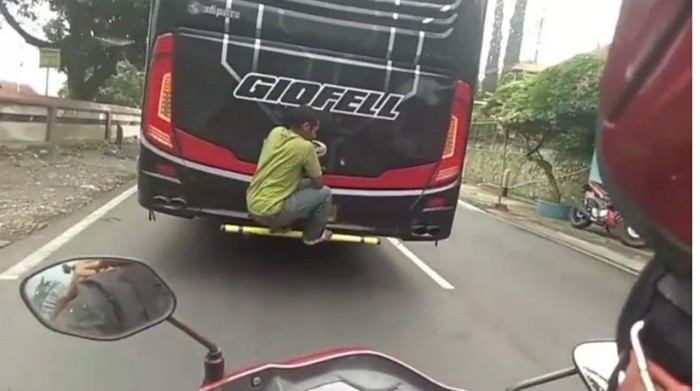 Video yang merekam pria bergelantungan di bus viral di media sosial.
