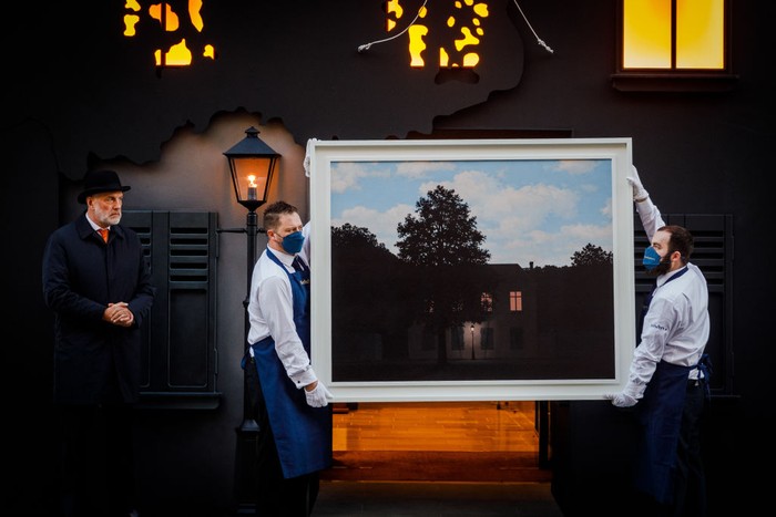 LONDON, ENGLAND - FEBRUARY 23:  Sotheby’s technicians hold René Magritte’s masterwork, L’empire des lumières, outside the auction house’s New Bond Street entrance at Sotheby's on February 23, 2022 in London, England. The painting goes on sale on March 2, when it will be offered with an estimate in excess of £45 million. To coincide with its exhibition, Sotheby’s London building has been transformed to resemble the artist’s masterpiece of Surrealism. (Photo by Tristan Fewings/Getty Images for Sotheby's)